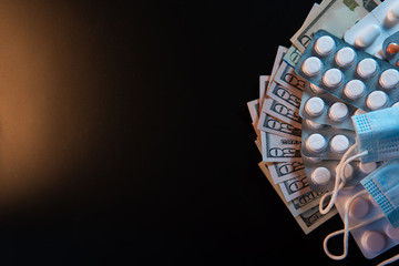 Cash, american dollar and pills, mask for respiratory protection. Excitement and panic, lack of protective equipment. Medicine and Business Investment in a Pandemic. Black background. Copy space.