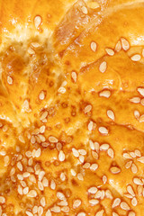 A crust of freshly baked bread with sesame seeds. The concept of bakery products. Abstract food background.