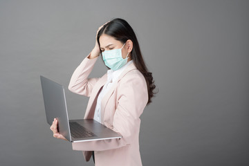 business woman with surgical mask is holding laptop computer