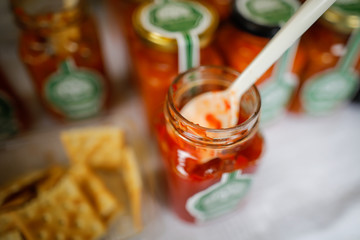 Shallow depth of field (selective focus) image with plastic spoon in a glass jar filled with a red sauce.