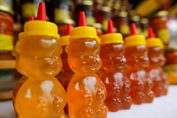 Bee honey in plastic bear shaped bottles on display in a market.