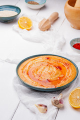 Hummus with paprika in a blue plate on a white wooden background. Traditional Middle eastern hummus. Healthy eating concept,