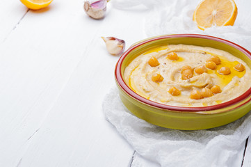 Bowl of arabic or lebanese vegetarian hummus.in green bowl on a white wooden background. Traditional Middle eastern hummus. Healthy eating concept,