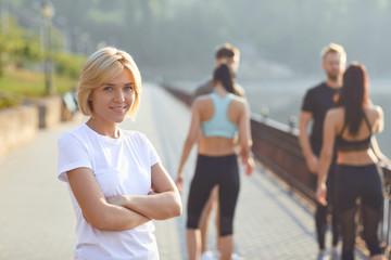 Sporty girl smiles on the background of friends athletes in the park