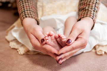 Pair of hans holding legs of newborn baby