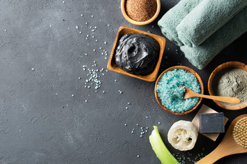 Spa. The concept of the bathroom. Natural cosmetics for the body and face. Sea salt, soaps of dead sea mud, scrub of coffee, loofah washcloth, massage brush on a dark table. Copy space.