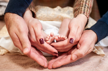 Pair of hans holding legs of newborn baby