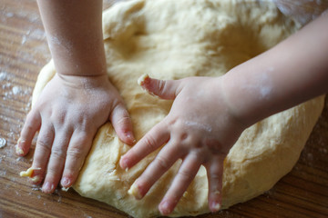Obraz na płótnie Canvas Child's hands knead yeast dough closeup