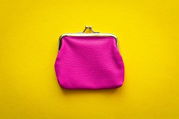Fashionable pink wallet on a yellow background. Close up.