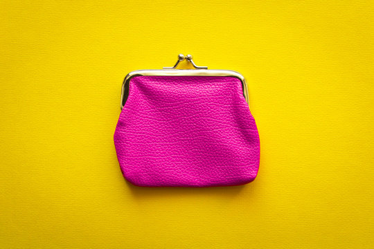 Fashionable pink wallet on a yellow background. Close up.