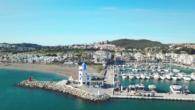 Beautiful Aerial panoramic view of "Puerto de la Duquesa" in MANILVA- Malaga SPAIN. Yachts and boats docked in the Harbour. Luxury Apartment Urbanisation and Restaurants . Forward and right rotation.