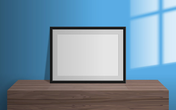 empty blank picture frame on wooden table window light effect on the wall mock up 