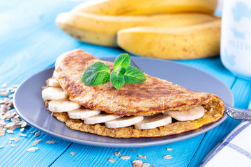Oatmeal pancakes with banana and mint on a blue wooden background