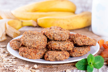 Homemade oatmeal cookies with banana and dried fruits on wooden table