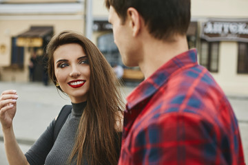 Young beautiful couple of lovers at the dating. Young woman with a perfect white smile and red lips and a handsome young man spending time together in the city