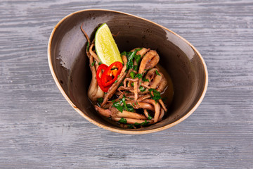 Boiled octopus with greens and red pepper, served with a slice of lime
