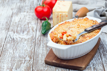 Spicy tomato jalapeno mac and cheese with mini penne pasta, in baking dish, horizontal, copy space