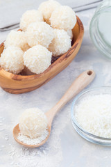 Homemade healthy raw paleo energy balls with shredded coconut, almond flour, coconut butter and sweetener in wooden bowl, vertical