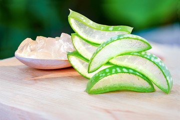 Aloe Vera Slices (Aloe barbadensis Mill.,Star cactus, Aloe, Aloin, Jafferabad or Barbados) fresh leaf with clear jelly in a spoon placed on a wooden table, A very useful herbal medicine for skin care