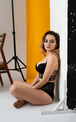 Beautiful busty girl wearing trendy lingerie is sitting on the floor with her eyes closed. Fashionable, advertising, lifestyle and commercial design.