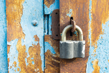 Metallic hanging lock hangs on locked doors of old iron gates