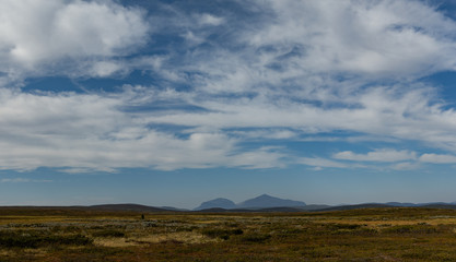 great visibility over an upland plain in sweden with a mountain range in background an blue sky with little clouds