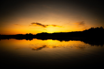 Obraz premium warm sunset of a lake in sweden with yellow colors and reflections on the water