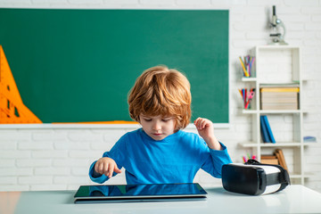 Schoolboy with digital tablet in school classroom. Pupil in class using digital tablet. Education. School for Talented pupil.