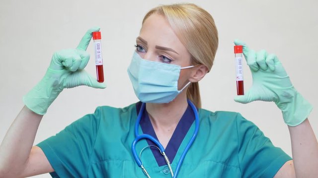 medical doctor nurse woman wearing protective mask and latex gloves - holding blood test tube