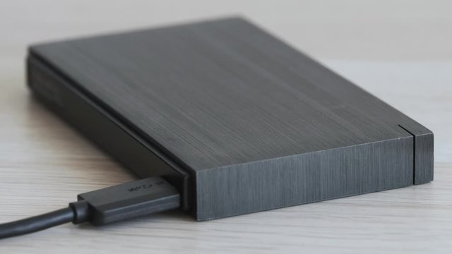 External Hard Drive On a Table, Led Light Flickering Softly - Solid Aluminium Casing HDD, Minimalist Design Composition - Macro Closeup