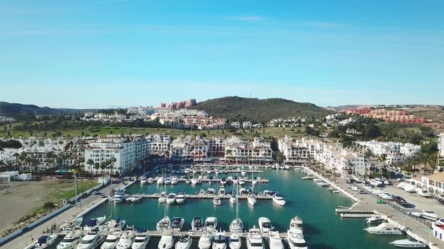 Beautiful Aerial panoramic view of "Puerto de la Duquesa" in MANILVA- Malaga SPAIN. Yachts and boats docked in the Harbour. Luxury Apartment Urbanisation and Restaurants . Drone pedestal up