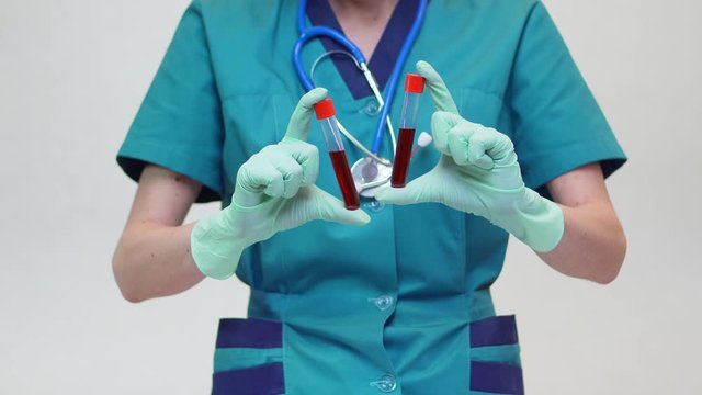 medical doctor nurse woman wearing protective mask and latex gloves - holding blood test tube