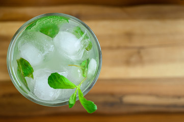 Refreshing alcoholic cocktail Mojito with white rum limes and soda mineral water on wooden board table background. Copy space. Bright summer drink with mint infused alcohol, ice cubes. Shot from top
