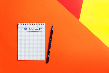Top view of office tools with blank notebook and pen on orange, yellow and red background. Space for text.