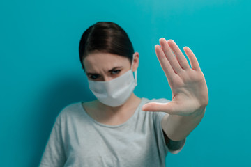 The girl in a medical mask makes a stop sign with her hand