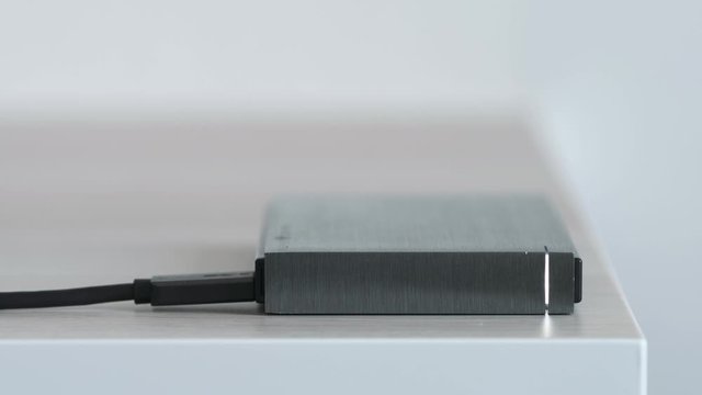 External Hard Drive On a Table, Led Light Flickering - Solid Aluminium Casing HDD, Minimalist Design Composition - Macro Closeup