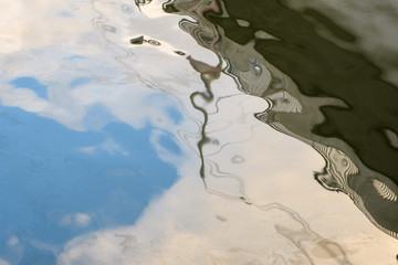 The surface of the water is stained with oil and oil, as well as the reflection of the blue sky and the promenade.