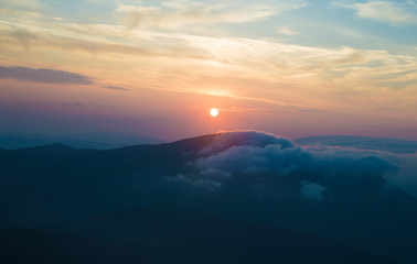 sunset in the mountains, mountains in the clouds in a haze
