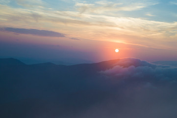 sunset in the mountains, mountains in the clouds in a haze