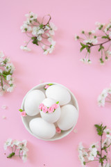 White eggs in bowl on pink background with flowers