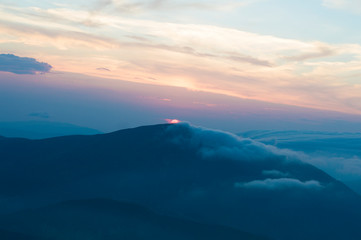 sunset in the mountains, mountains in the clouds in a haze