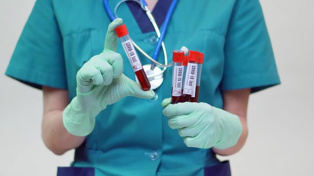 medical doctor nurse woman wearing protective mask and latex gloves - holding blood test tube