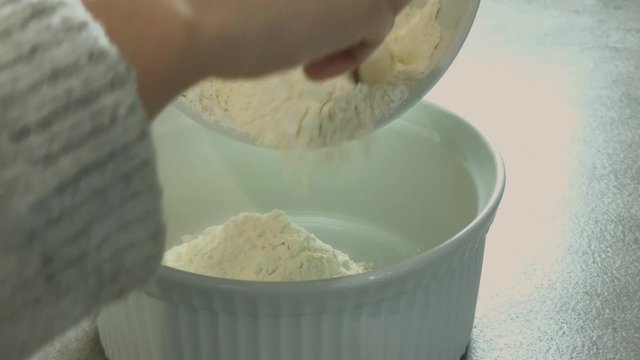 Versement de farine dans saladier  ( plan qui recule ) 