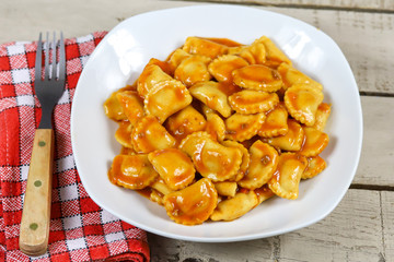 assiette de raviolis à la sauce tomate sur une table en bois