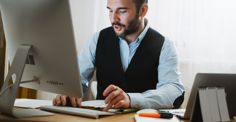 bearded businessman online communication work process, consultant looking in monitor computer at home workplace. man working at social distance, online education