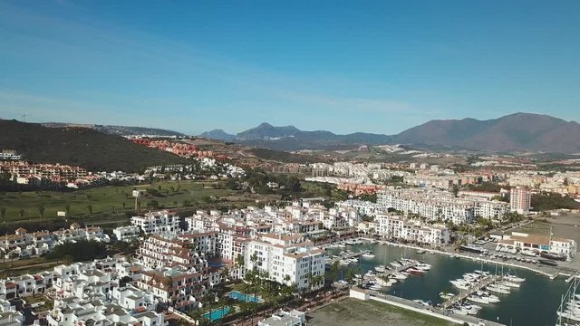 Beautiful Aerial panoramic view of "Puerto de la Duquesa" in MANILVA- Malaga SPAIN. Yachts and boats docked in the Harbour. Luxury Apartment Urbanisation and Restaurants . Drone going forward 