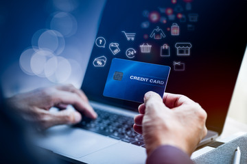 Man's hand holding credit card while using laptop online with shopping illustration icon