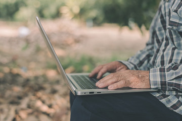 Asian farmer working through a laptop in his farm