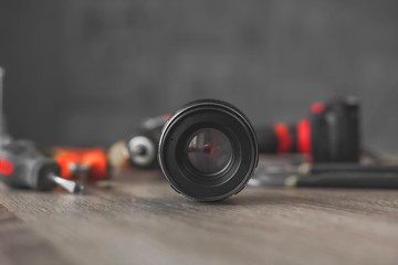 black lens from the camera lies among a pile of tools