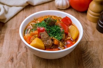 Lagman asian soup on white plate on wooden table
